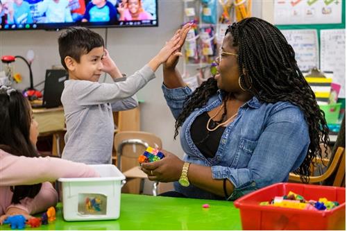 Volunteer high fives a student